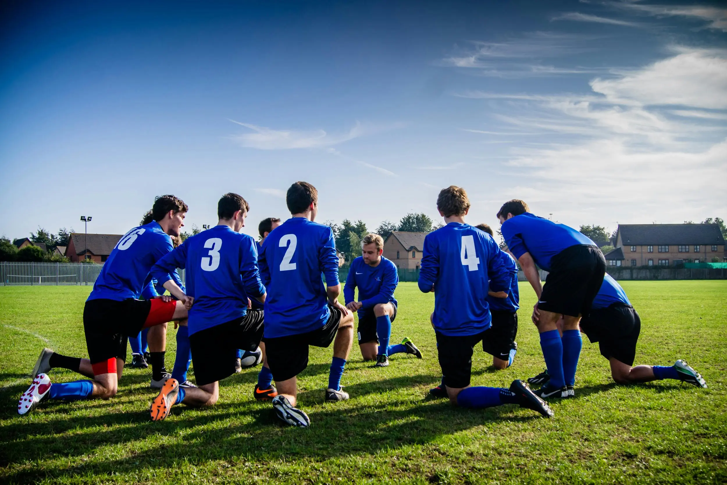 A team of soccer players forms a huddle on the field, collaborating and preparing for the next play.