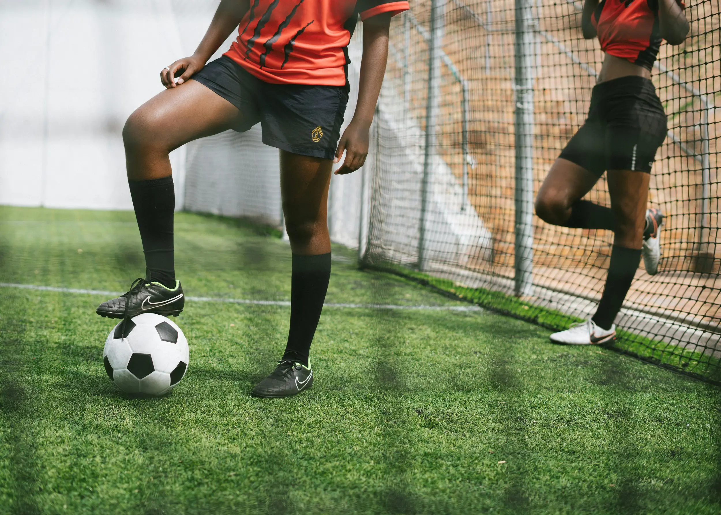 Two young women playing soccer on a vibrant field, showcasing teamwork and athleticism.