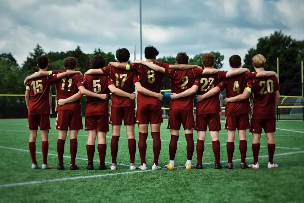A group of boys in maroon uniforms stands together on a soccer field, ready for their game.