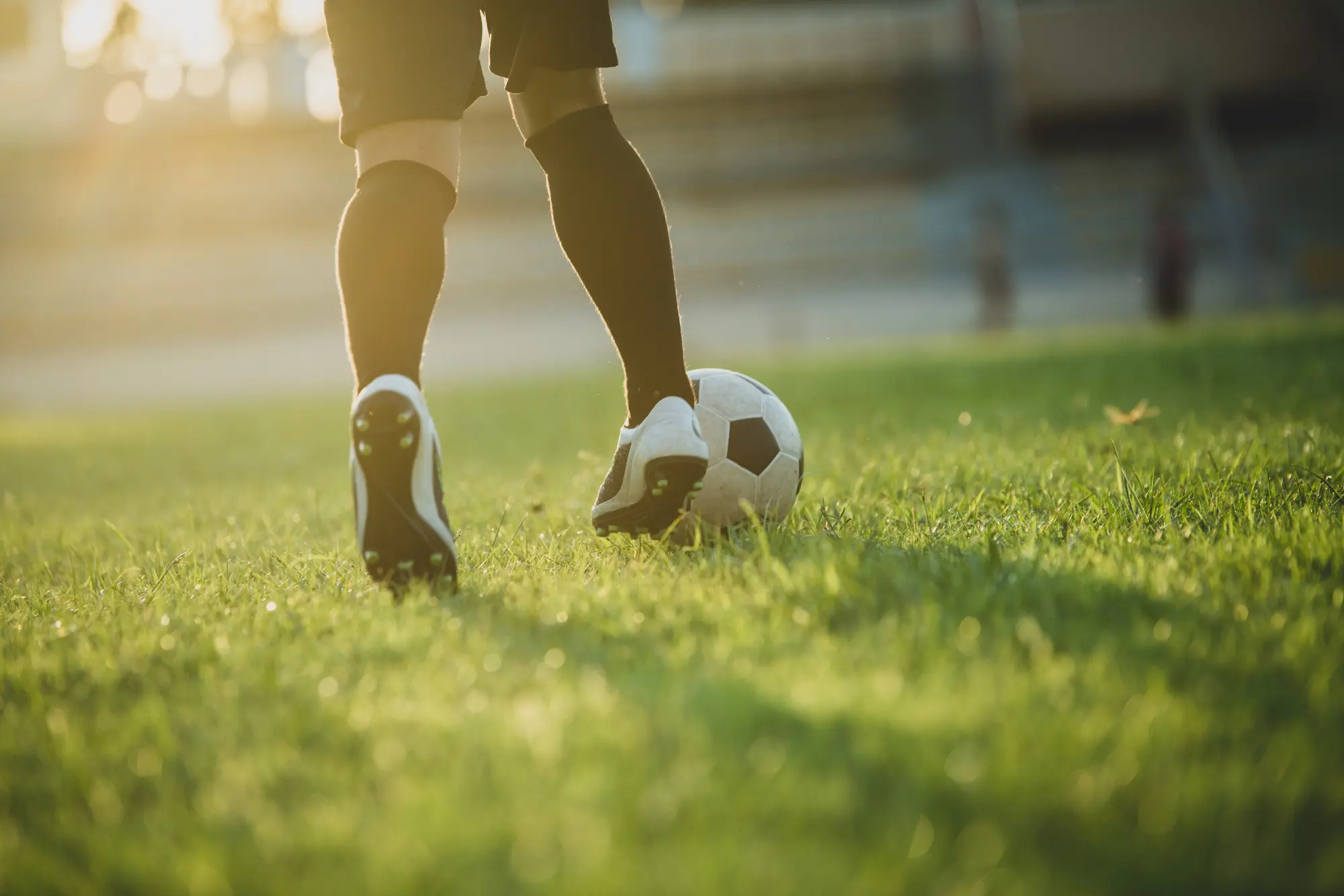 A soccer player skilfully kicks a ball on a lush green grass field during a match.