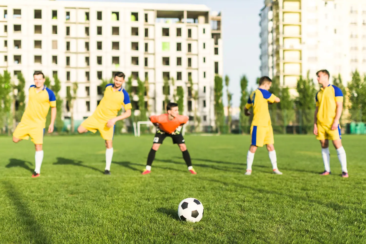 Soccer players wearing yellow and blue uniforms compete on a vibrant green field during a match.