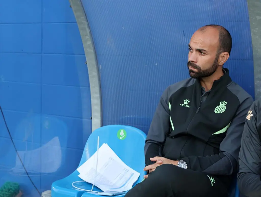 Luis Vicente Mateo, sitting watching soccer training