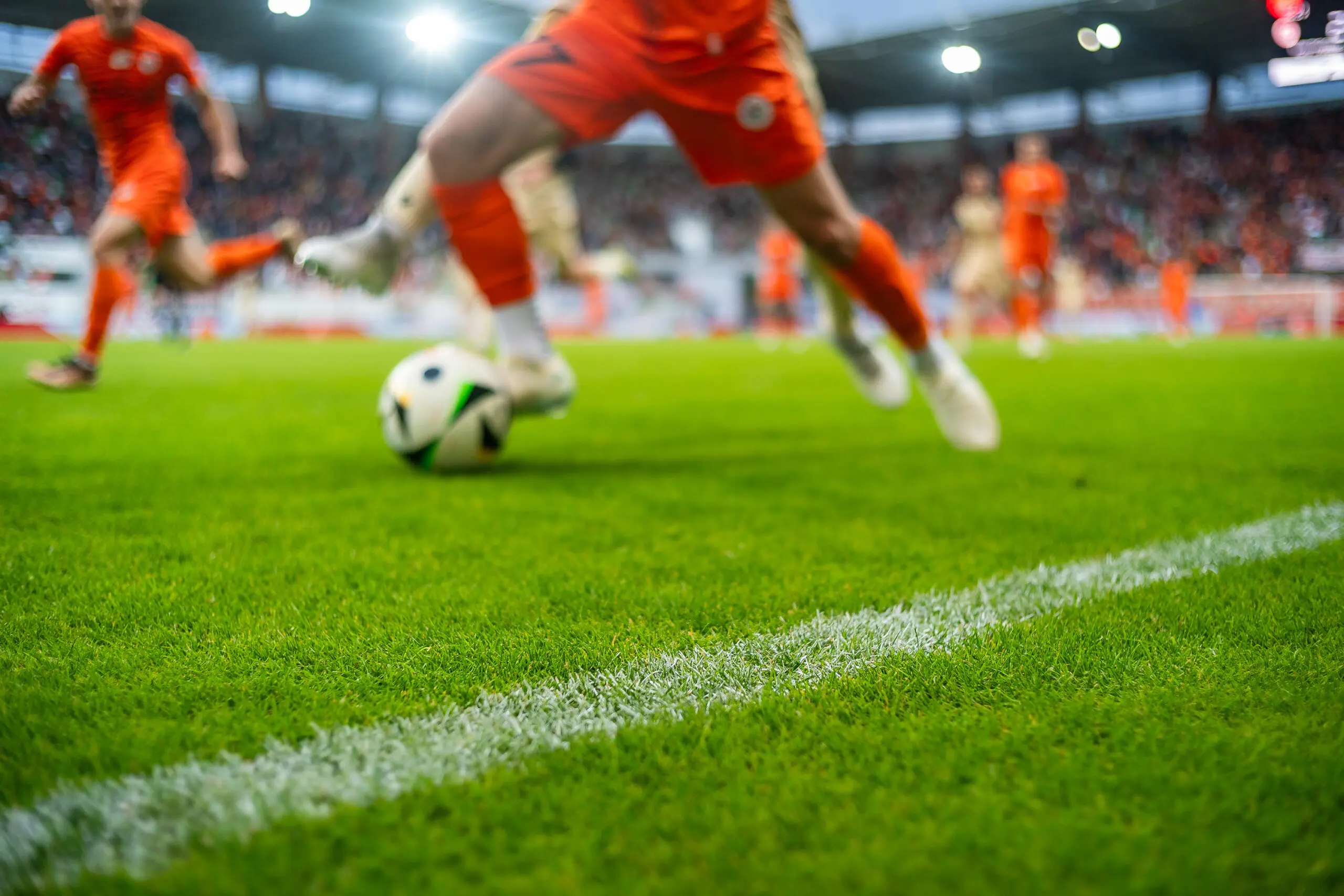 photo of players feet running with a ball on the pitch