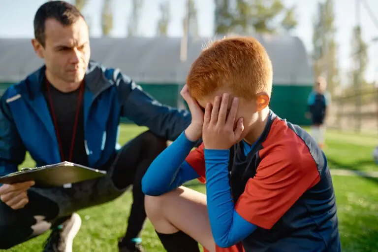 Upset youth soccer player being consoled by coach