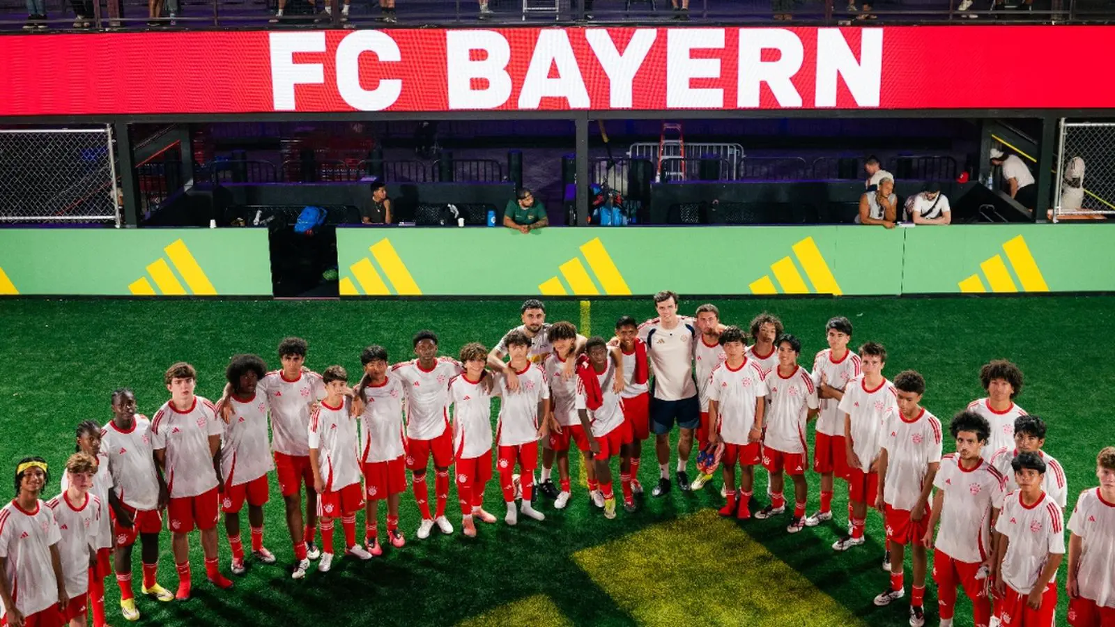 Fifty youth players in FC Bayern kits gather on the field at the FC Bayern combine at Brooklyn Bridge Park, New York City.