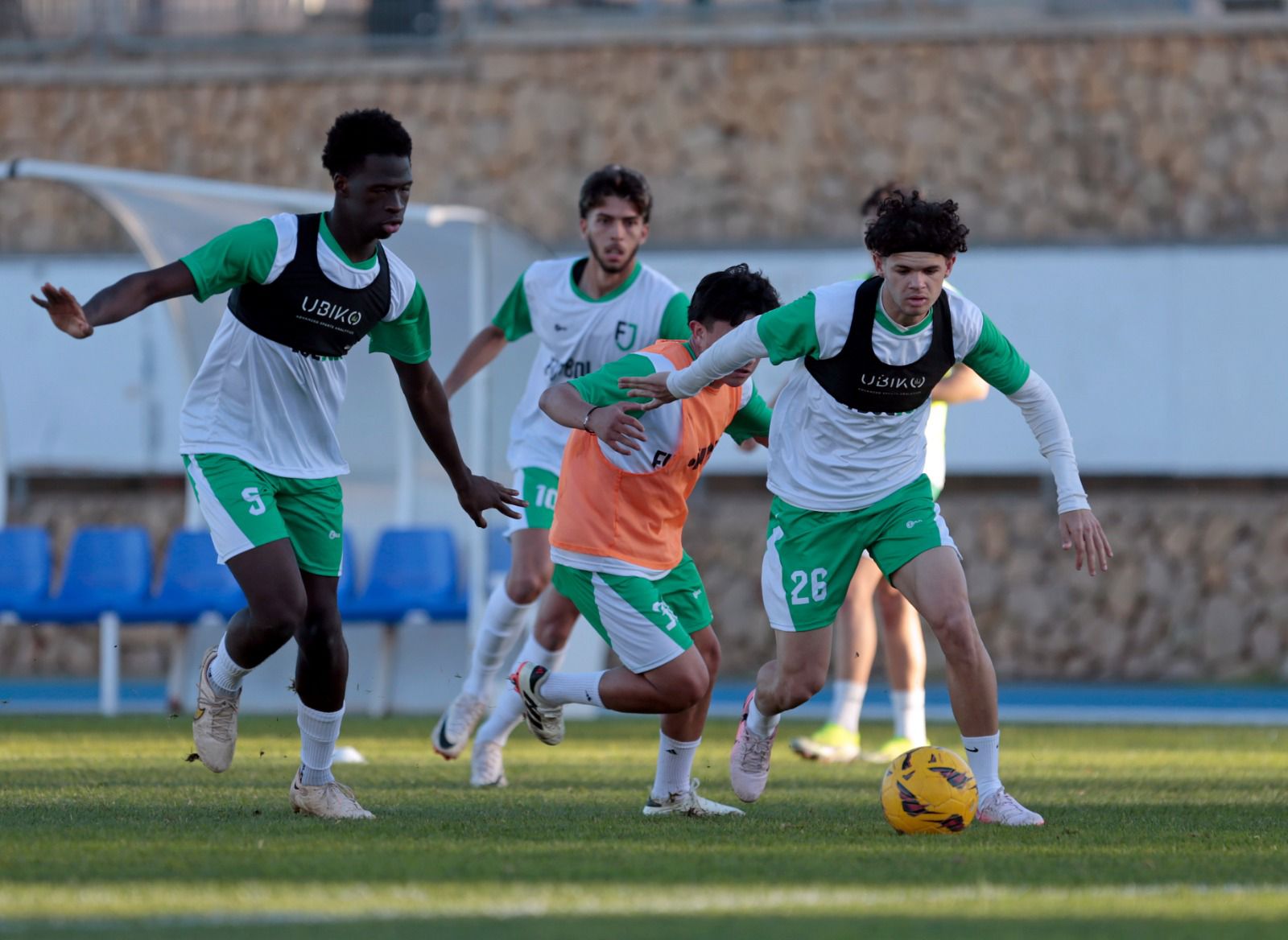 Soccer players in green and white uniforms compete on the field during an intense match.